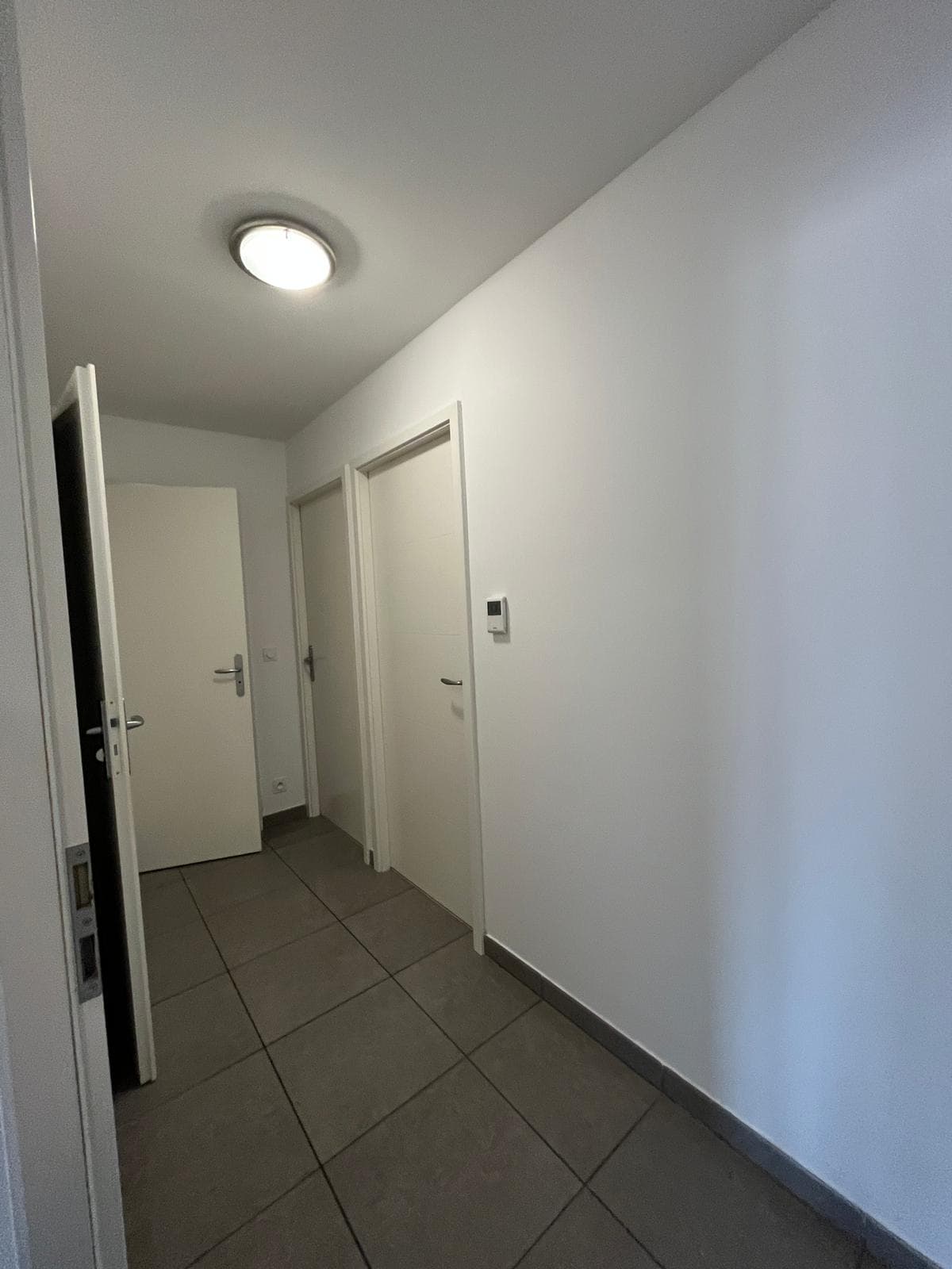 Couloir d'entrée avec carrelage et accès aux chambres